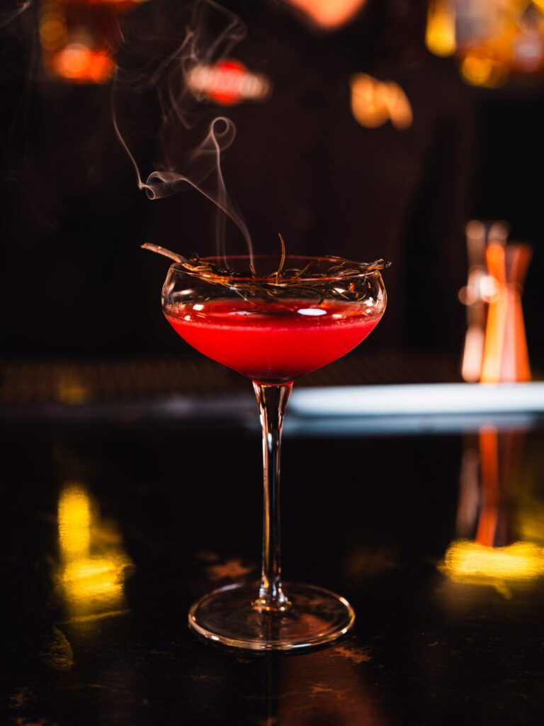 Fotografía gastronómica de cóctel rojo ahumado en copa martini con romero en los mochis sinaloa